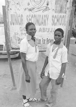 L-R: Mrs. Juliana Godwin with her son, Sam Godwin, in front of Junior Secondary School, Gosa, Abuja signboard 